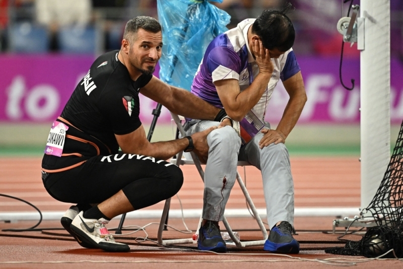 Trọng tài Huang tỏ ra đau đớn khi bị ném búa trúng chân Trong tai Huang to ra dau don khi bi nem bua trung chan